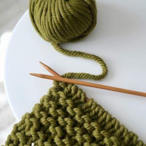 Home Green yarn and knitting needles on a table, showcasing crafting creativity.